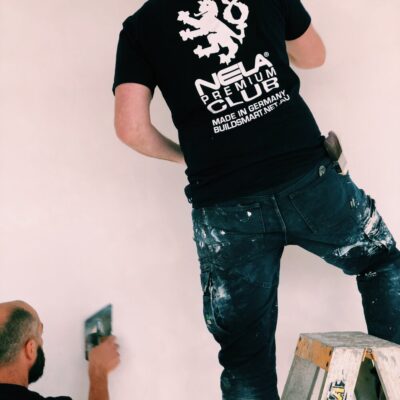 NELA Premium T-Shirt – Official NELA Club Workwear NELA Premium T-Shirt black with white NELA logo, worn by plasterers on site